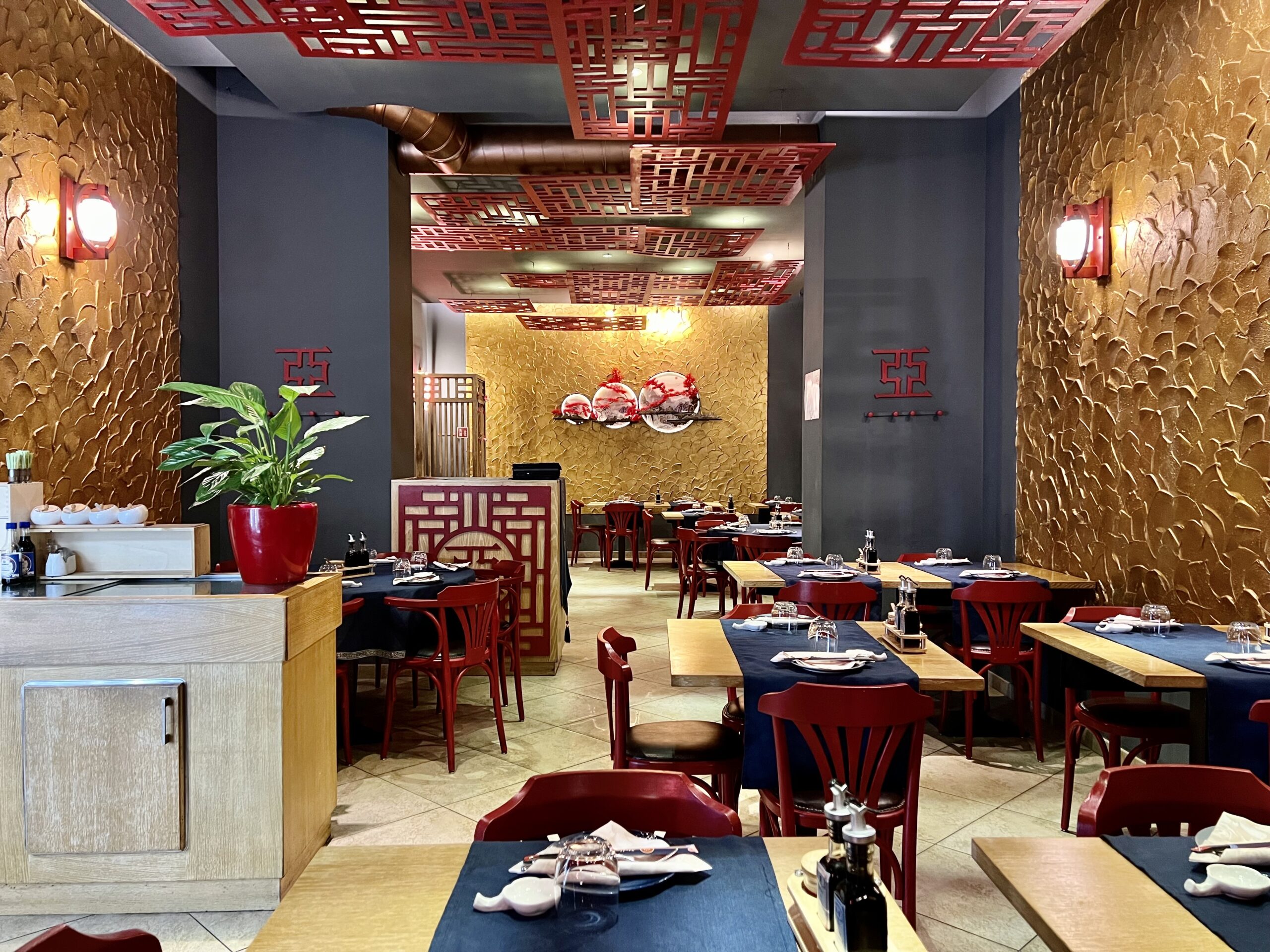 Sala interna del ristorante con tavoli apparecchiati e paraventi in legno traforato